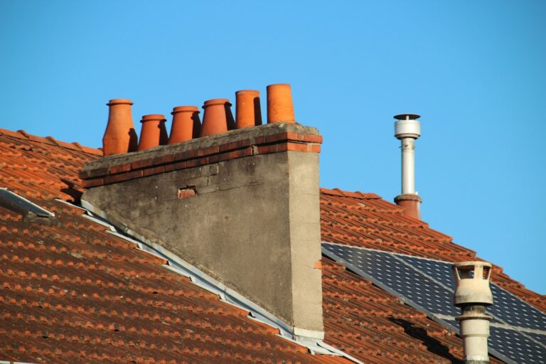 Metal roof flashing installed around a chimney and wall intersection with shingles layered over the edges.